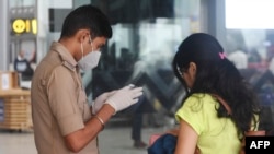 FILE - An Indian border officer checks the documents of a traveler at Netaji Subhas Chandra Bose International Airport in Kolkata, India, March 7, 2020. In a visa spat, India and China have expelled nearly all of each other’s journalists in recent weeks.