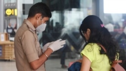 FILE - An Indian border officer checks the documents of a traveler at Netaji Subhas Chandra Bose International Airport in Kolkata, India, March 7, 2020. In a visa spat, India and China have expelled nearly all of each other’s journalists in recent weeks.