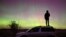 Seorang pria berdiri di atas mobil sambil melihat aurora yang dipicu oleh lontaran massa koronal matahari yang menerangi langit di wilayah barat daya Siberia Omsk, Rusia. (Reuters)&nbsp;