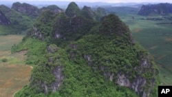This photo provided by researchers shows a mountain where fossils of Gigantopithcus blacki were found in caves in the Guangxi region of southern China.
