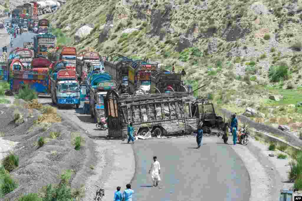 People look at a charred vehicle near a collapsed railway bridge a day after a blast by separatist militants at Kolpur in Bolan district, Balochistan province, Pakistan.