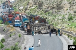 People look at a charred vehicle near a collapsed railway bridge a day after a blast by separatist militants at Kolpur in Bolan district, Balochistan province, Pakistan, Aug. 27, 2024.