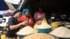 FILE - Founder of EasyShop EasyCook, Saudat Salami (L) looks at melon seeds for sale at a food market in Lagos, Nigeria, March 4, 2020.