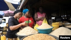 FILE - Founder of EasyShop EasyCook, Saudat Salami (L) looks at melon seeds for sale at a food market in Lagos, Nigeria, March 4, 2020.