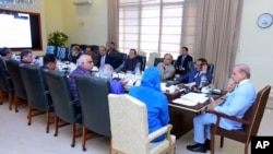 Prime Minister Prime Minister Shahbaz Sharif, right, chairs a meeting regarding a crackdown against human smugglers, in Islamabad, Pakistan, June 21, 2023. (Pakistani Press Information Department via AP)