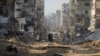 Palestinians walk between the remains of destroyed buildings following the Israeli bombardment on the main road of Gaza City on Jan. 2, 2024.