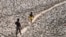 FILE - A man and a boy walk across the dried bed of the Yamuna River in New Delhi, India, May 2, 2022. In an annual climate report, the World Meteorological Organization said Nov. 2, 2023, that the climate crisis was generating a global health crisis.