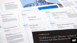 FILE - Pages from a Carlyle Group 2021 report on its financial risk from greenhouse gas emissions are photographed Tuesday, Sept. 20, 2022. Documents and contracts often contain what is called "boilerplate language." (AP Photo/Jon Elswick)