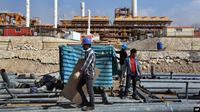 FILE - Construction workers move materials at a gas refinery in Asalouyeh, Iran, on Jan. 22, 2014. The Iranian parliament voted on Nov. 19, 2023, to raise the retirement age for men from 60 to 62.