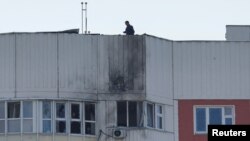 A man inspects damage atop a multi-story apartment block following a reported drone attack in Moscow, May 30, 2023.