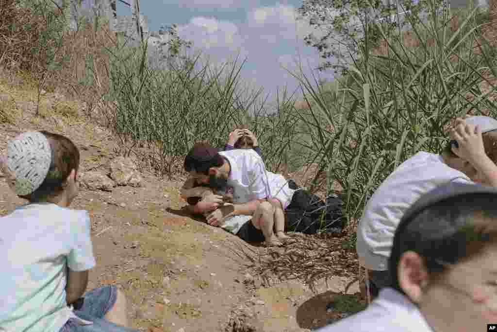 Israelis take cover as a siren sounds a warning of incoming rockets fired from the Gaza Strip in Rehovot, Israel. (AP Photo/Dor Kedmi)