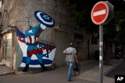 A man in Tel Aviv walks past graffiti of Joe Biden that depicts the U.S. president as a superhero defending Israel on Oct. 30, 2023. Biden, whose popularity in Israel has soared because of his support in its war with Hamas, has repeatedly warned Iran not to escalate the conflict.