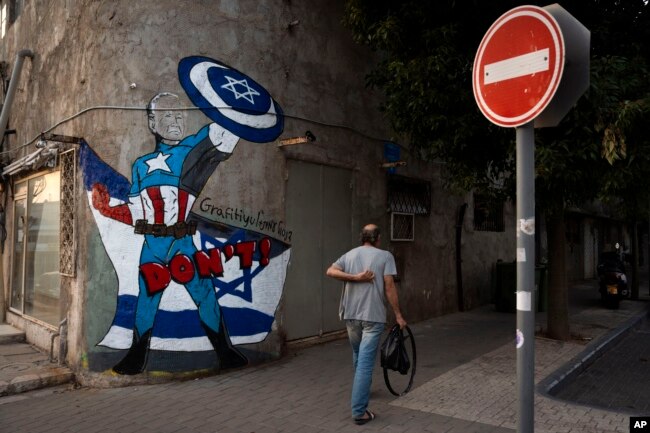 A man in Tel Aviv walks past graffiti of Joe Biden that depicts the U.S. president as a superhero defending Israel on Oct. 30, 2023. Biden, whose popularity in Israel has soared because of his support in its war with Hamas, has repeatedly warned Iran not to escalate the conflict.