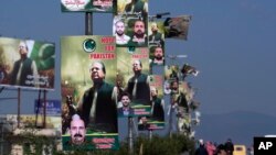 পাকিস্তানের রাওয়ালপিন্ডিতে একটি হাইওয়ের পাশে স্থাপিত পাকিস্তানের স্বেচ্ছায় নির্বাসিত প্রাক্তন প্রধানমন্ত্রী নওয়াজ শরীফের জন্য স্বাগত ব্যানারের পাশ দিয়ে মোটরসাইকেল এবং গাড়ি চলে যাচ্ছে। ১৯ অক্টোবর, ২০২৩। 