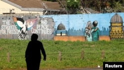 Homem atravessa uma estrada em frente a um mural que simboliza a liberdade e a paz entre Israel e palestinianos, em Rondebosch, Cidade do Cabo, África do Sul, 11 de outubro de 2023. REUTERS/Esa Alexander