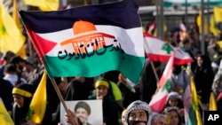 Seorang pendukung kelompok Hizbullah yang didukung Iran mengibarkan bendera Palestina dengan kata-kata Arab yang bertuliskan: "Yerusalem kami datang," dalam rapat umum di Beirut, Lebanon, Jumat 3 November 2023.