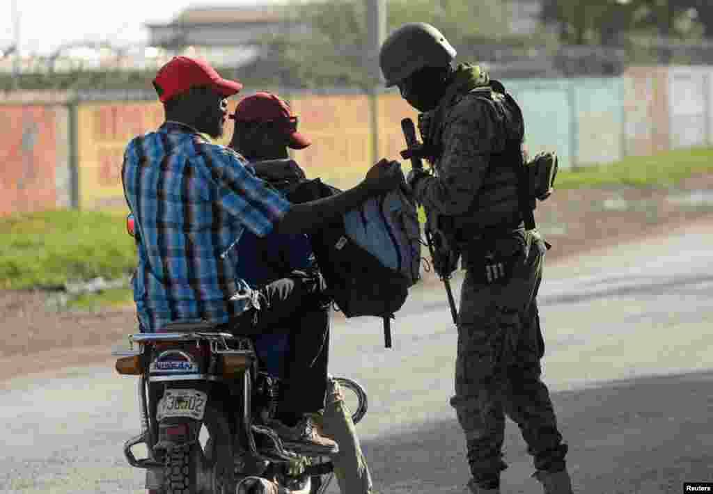 Un soldado revisa las pertenencias de una persona en busca de armas en un puesto de control, mientras Haití continúa en estado de emergencia.