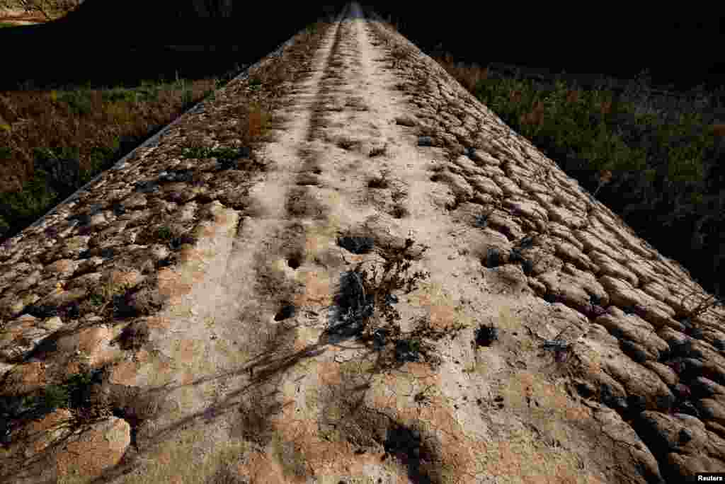 A path emerges from the dry cracked bed of La Baells reservoir, currently at 24% of its capacity near Cercs, north of Barcelona, Spain, Nov. 21, 2023.