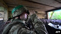 A Ukrainian border guard looks through binoculars from his position on the border with Russia in the Kharkiv region on July 5, 2023.