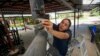 FILE - Abigail Lopez, a member of cooperative Pixcatl, removes a filter from a water collector system at a community garden in Mexico City, July 14, 2024. 