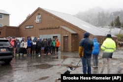 A group of cross country athletes, who had traveled from Davis, California, huddle after their practice was canceled due to wet and snowy conditions in Donner Summit, California, Aug. 24, 2024.