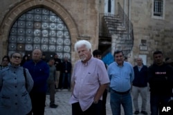 FILE - Garo Nalbandian, an 80-year-old photojournalist, center, listens to a speaker during an Armenian community protest of a contentious deal that stands to displace him and other residents of the Armenian Quarter in the Old City of Jerusalem, May 19, 2023.