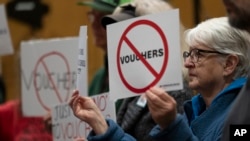 FILE - Mirabelle Stoedter holds a sign against school vouchers during a news conference, Nov. 28, 2023, in Nashville, Tenn., where Tennessee Gov. Bill Lee presented the Education Freedom Scholarship Act of 2024.