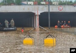 In this photo provided by South Korea National Fire Agency, rescuers search for survivors along a road submerged by floodwaters leading to an underground tunnel in Cheongju, South Korea, July 16, 2023.