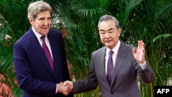 Utusan Iklim AS John Kerry dan Direktur Kantor Komisi Urusan Luar Negeri Komite Sentral Partai Komunis China Wang Yi (kanan) berjabat tangan sebelum pertemuan di Aula Besar Rakyat di Beijing pada 18 Juli 2023. (Foto : AFP)