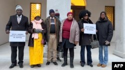 Plaintiffs pose at the entrance of the Swiss Federal Criminal Court during the opening day of the trial of Ousman Sonko, January 8, 2024.