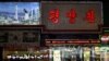 Seorang pekerja restoran Korea Utara (Kiri) berdiri di pintu masuk sebuah restoran di Shenyang, Provinsi Liaoning, China, 31 Maret 2023. (Foto: AFP/JADE GAO)