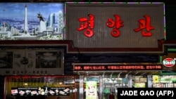 Seorang pekerja restoran Korea Utara (Kiri) berdiri di pintu masuk sebuah restoran di Shenyang, Provinsi Liaoning, China, 31 Maret 2023. (Foto: AFP/JADE GAO)