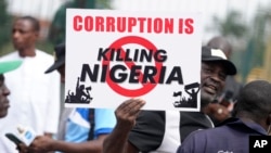 A man holds a banner during a protest against economic hardship, in Lagos, Nigeria, Aug 2, 2024.