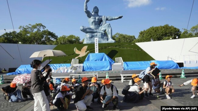 Visitantes en el Parque de la Paz se agachan tras una alerta de sismo en Nagasaki, en el oeste de Japón, el jueves 8 de agosto de 2024