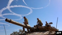 Israeli troops stand atop a tank on the border with the Gaza Strip on Nov. 30, 2023, on the seventh day of a truce in battles between Israel and Hamas militants.