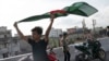 A young man celebrates with a national flag after the resignation of prime minister Sheikh Hasina in Dhaka, Bangladesh, Aug. 6, 2024