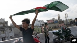 A young man celebrates with a national flag after the resignation of prime minister Sheikh Hasina in Dhaka, Bangladesh, Aug. 6, 2024