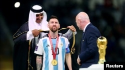Lionel Messi de Argentina, el emir de Qatar, el jeque Tamim bin Hamad Al Thani, y el presidente de la FIFA, Gianni Infantino, durante la ceremonia de entrega del trofeo de la Copa Mundial de Fútbol 2022.