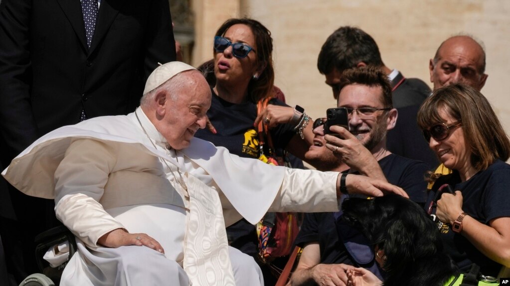 ARCHIVO - El papa Francisco acaricia a un perro guía durante su audiencia general semanal en la Plaza de San Pedro, en el Vaticano, el 31 de mayo de 2023.