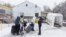 FILE - A family crosses into Canada at Roxham Road, an unofficial crossing point from New York state to Quebec for asylum-seekers, in Champlain, N.Y., March 25, 2023. 