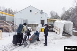 FILE - A family crosses into Canada at Roxham Road, an unofficial crossing point from New York State to Quebec for asylum-seekers, in Champlain, N.Y., March 25, 2023. (REUTERS/Carlos Osorio)