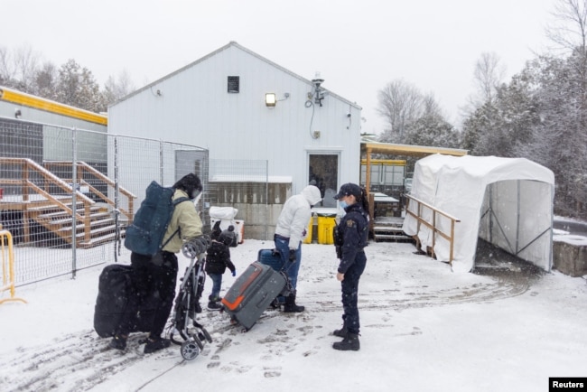 FILE - A family crosses into Canada at Roxham Road, an unofficial crossing point from New York State to Quebec for asylum-seekers, in Champlain, N.Y., March 25, 2023. (REUTERS/Carlos Osorio)