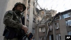 A Ukrainian serviceman stands in front of a building which was heavily damaged by a Russian airstrike in Kherson, Ukraine, June 15, 2023. 