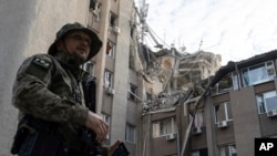 A Ukrainian serviceman stands in front of a building which was heavily damaged by a Russian airstrike in Kherson, Ukraine, June 15, 2023. 