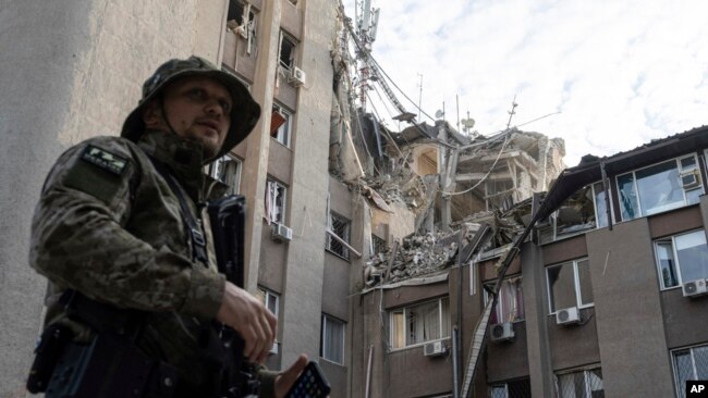 Un militar ucraniano se para frente a un edificio que resultó gravemente dañado por un ataque aéreo ruso en Jersón, Ucrania, el 15 de junio de 2023.