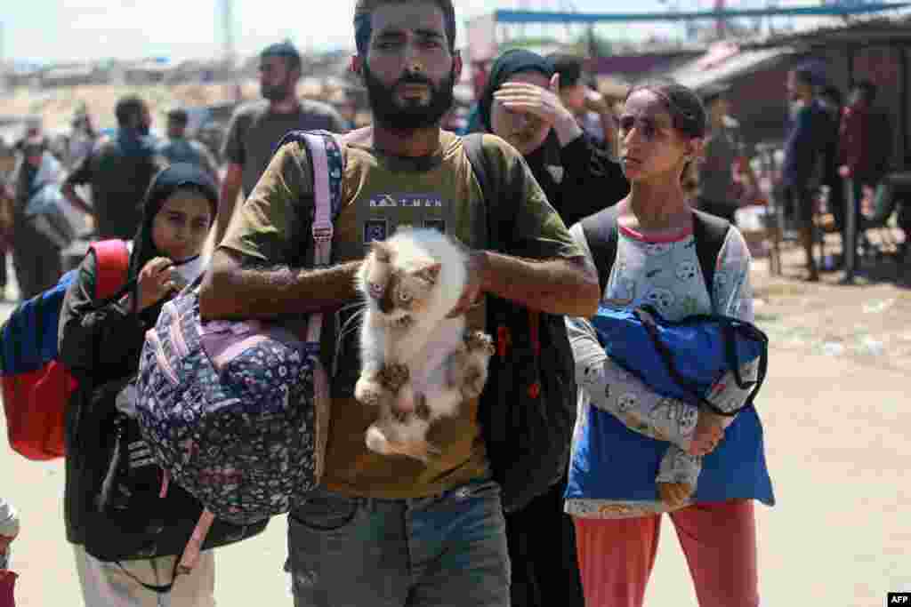 A Palestinian man carries a cat as he flees with others a makeshift camp for displaced people in Khan Yunis in the southern Gaza Strip after Israeli tanks took position on a hill overlooking the area.