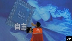 资料照：一名工人在上海举办的世界人工智能大会上检查中国科技公司中科曙光展示的芯片与自主字样的屏幕。（2023年7月5日）