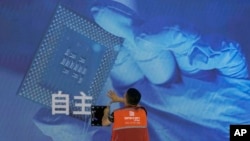 一名工人在上海举办的世界人工智能大会上检查中国科技公司中科曙光展示的芯片和自主字样的屏幕。（2023年7月5日）
