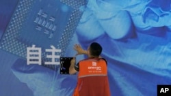 一名工人在上海舉辦的世界人工智能大會上檢查中國科技公司中科曙光展示的芯片和自主字樣的屏幕。（2023年7月5日）