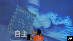 一名工人在上海舉辦的世界人工智能大會上檢視中國科技公司中科曙光展示的芯片和“自主” 字樣的螢幕。 （2023年7月5日）